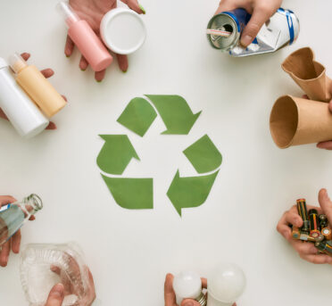 Your life improved. Top view of many hands holding different waste, garbage types with recycling sign made of paper in the center over white background